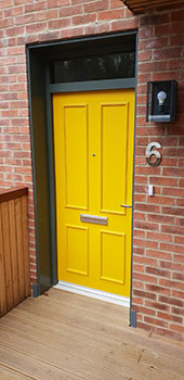 bespoke timber exterior door set, yellow with paneling and toplight