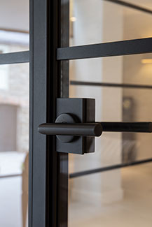 Black, round lever handle on a crittall style steel door