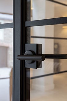Black, round lever handle on a steel door